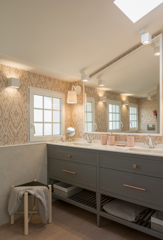 Inspiration for a large traditional kids bathroom in Bilbao with raised-panel cabinets, grey cabinets, an alcove shower, a wall-mount toilet, pink tile, pink walls, laminate floors, an undermount sink, engineered quartz benchtops and a hinged shower door.