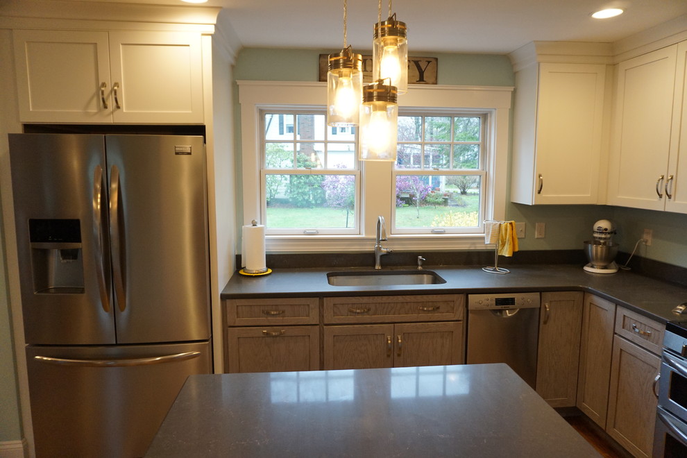 Example of a mid-sized transitional u-shaped medium tone wood floor eat-in kitchen design in Boston with an undermount sink, shaker cabinets, gray cabinets, quartz countertops, black backsplash, stainless steel appliances and an island