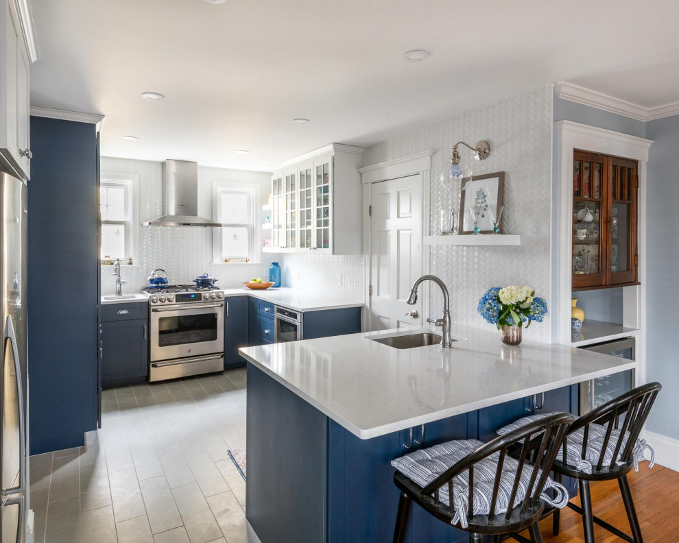 Example of a mid-sized transitional u-shaped porcelain tile and gray floor eat-in kitchen design in Boston with an undermount sink, shaker cabinets, blue cabinets, quartz countertops, white backsplash, subway tile backsplash, stainless steel appliances, a peninsula and white countertops