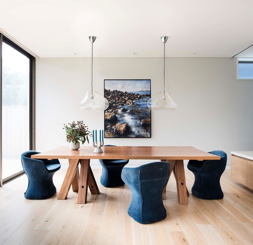 Modern wood dining table with blue upholstered pedestal chairs 