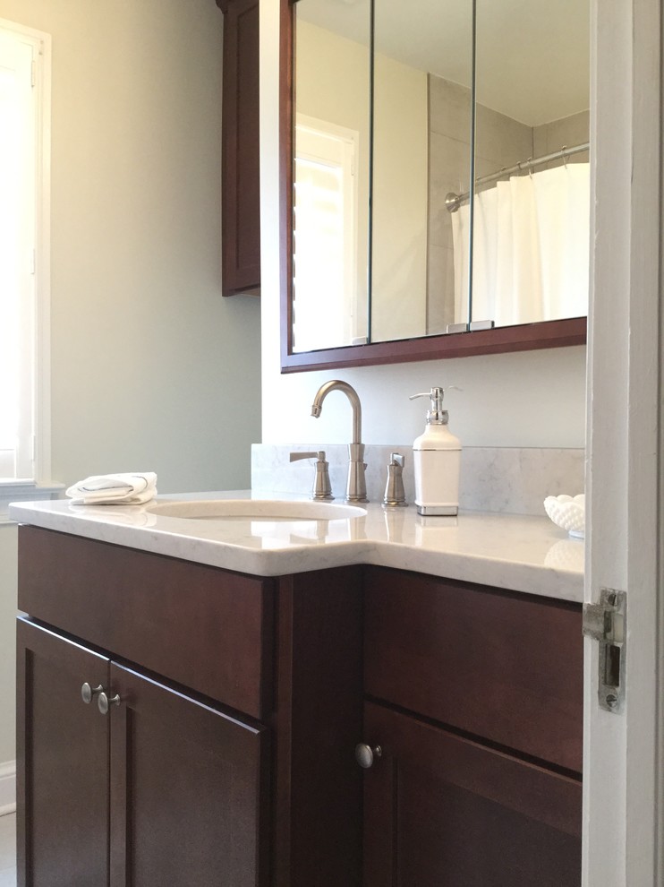Photo of a mid-sized transitional bathroom in DC Metro with an undermount sink, shaker cabinets, dark wood cabinets, engineered quartz benchtops, an alcove tub, a shower/bathtub combo, a two-piece toilet, gray tile, porcelain tile and porcelain floors.
