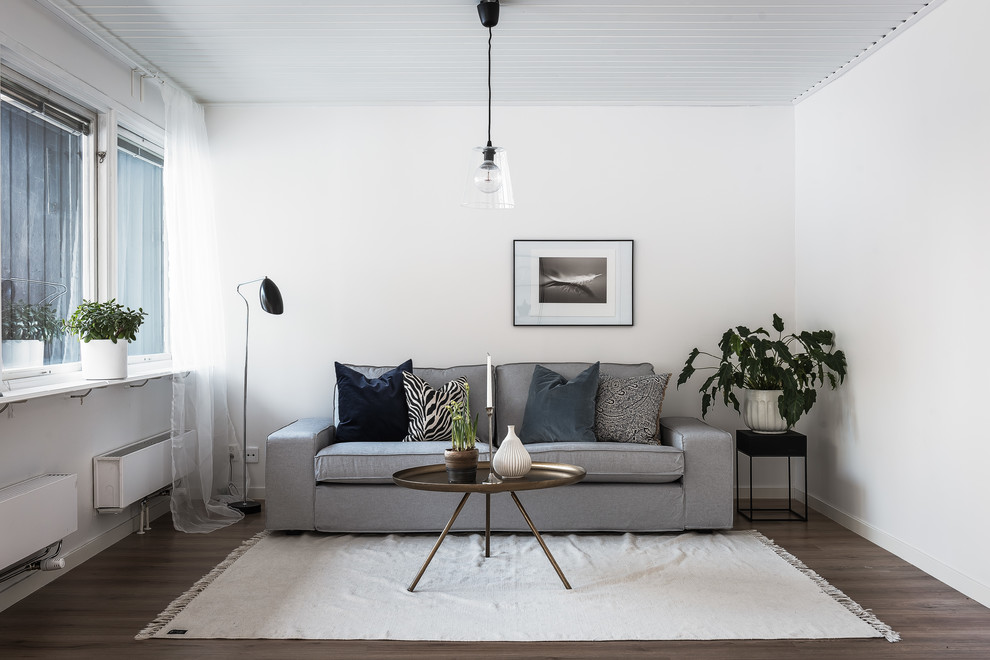 Photo of a scandinavian living room in Orebro with white walls and dark hardwood floors.