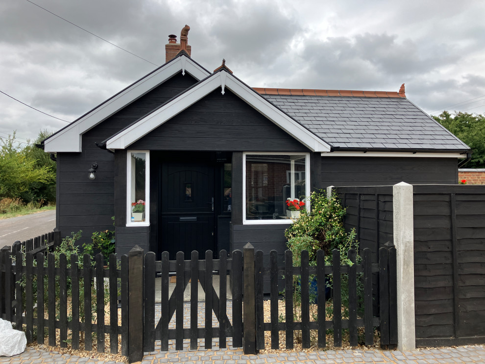 Small transitional entryway in Dorset with black walls, a dutch front door, a black front door, grey floor, vaulted and planked wall panelling.