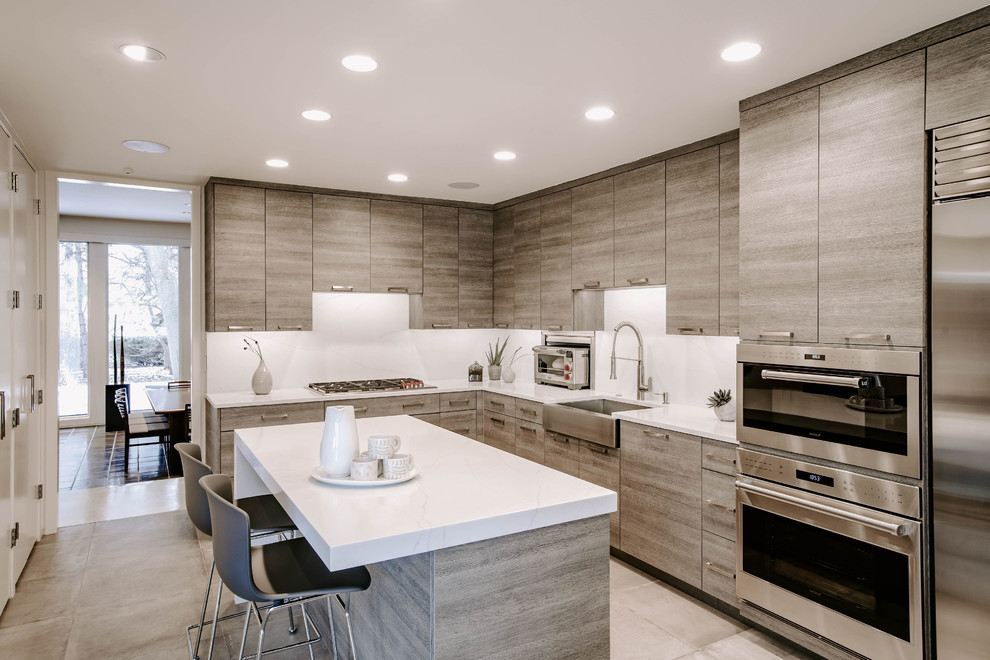 Design ideas for a mid-sized contemporary l-shaped eat-in kitchen in Detroit with a farmhouse sink, flat-panel cabinets, grey cabinets, quartz benchtops, white splashback, stainless steel appliances, porcelain floors, with island, grey floor and white benchtop.