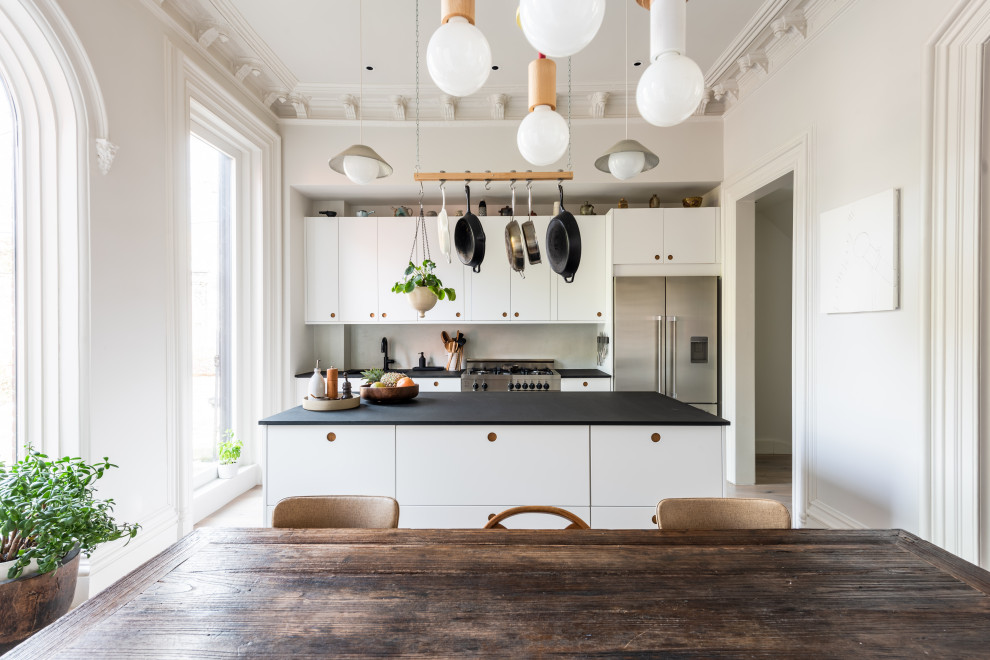 Свежая идея для дизайна: кухня-гостиная в скандинавском стиле с плоскими фасадами, островом и черной столешницей - отличное фото интерьера