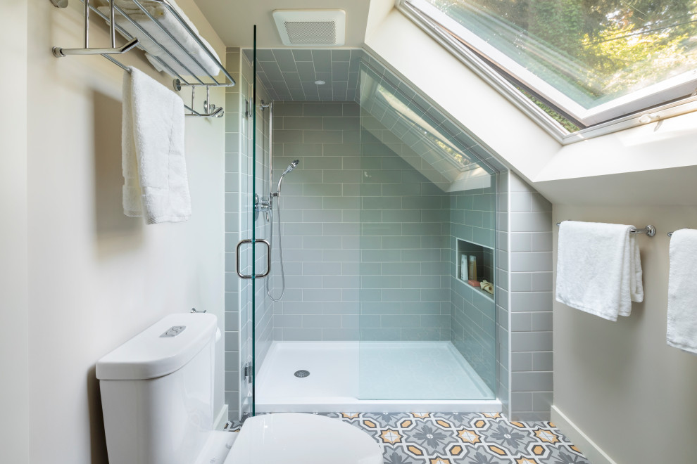 This is an example of a mid-sized transitional 3/4 bathroom in Seattle with an alcove shower, a two-piece toilet, gray tile, ceramic tile, beige walls, porcelain floors, grey floor, a hinged shower door and a niche.