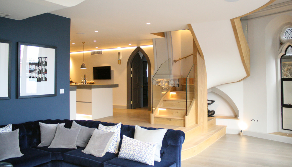 Contemporary living room in London with a concealed tv, white walls and light hardwood floors.