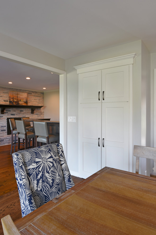Example of a transitional l-shaped medium tone wood floor eat-in kitchen design in Orange County with a double-bowl sink, shaker cabinets, white cabinets, marble countertops, gray backsplash, glass tile backsplash, stainless steel appliances and an island