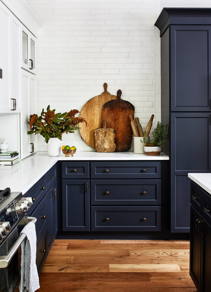 Example of a large country u-shaped medium tone wood floor and brown floor open concept kitchen design in Austin with an undermount sink, shaker cabinets, blue cabinets, quartz countertops, white backsplash, ceramic backsplash, stainless steel appliances, an island and white countertops