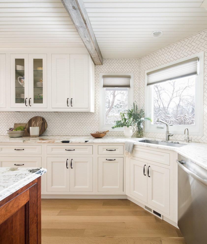 This is an example of a large transitional u-shaped open plan kitchen in Denver with an undermount sink, recessed-panel cabinets, white cabinets, white splashback, porcelain splashback, stainless steel appliances, medium hardwood floors, with island, brown floor, white benchtop and timber.