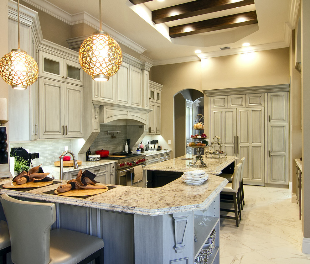 Photo of a large traditional eat-in kitchen in Tampa with an undermount sink, raised-panel cabinets, grey cabinets, granite benchtops, grey splashback, glass tile splashback, panelled appliances, marble floors, with island and white floor.