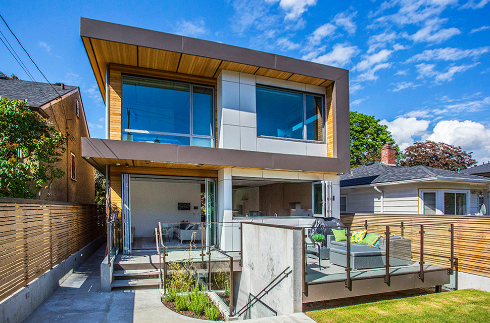 Photo of a small contemporary two-storey white house exterior in Vancouver with mixed siding and a flat roof.