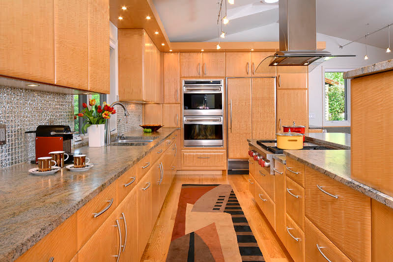 Photo of a large traditional u-shaped eat-in kitchen in Denver with an undermount sink, flat-panel cabinets, medium wood cabinets, granite benchtops, metallic splashback, mosaic tile splashback, stainless steel appliances, medium hardwood floors, with island, brown floor and multi-coloured benchtop.