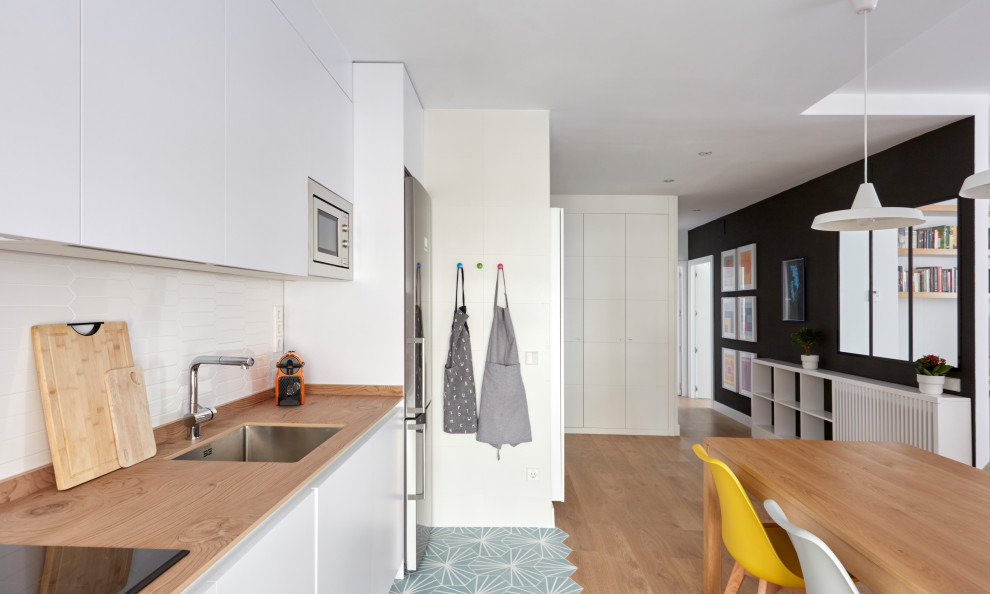 Inspiration for a mid-sized modern kitchen in Madrid with a single-bowl sink, flat-panel cabinets, white cabinets, granite benchtops, white splashback, ceramic splashback, white appliances, ceramic floors, turquoise floor and grey benchtop.