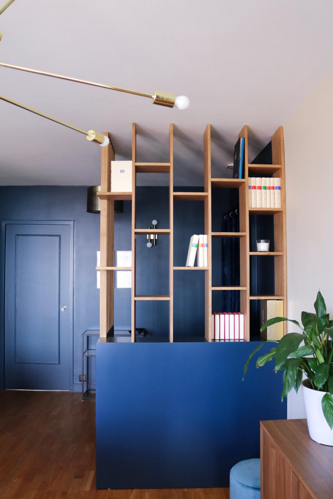 Photo of a mid-sized modern open concept living room in Paris with a library, blue walls and laminate floors.