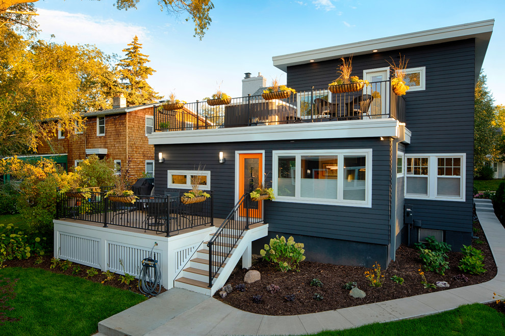 Photo of a mid-sized contemporary two-storey grey house exterior in Minneapolis with vinyl siding, a flat roof and a shingle roof.