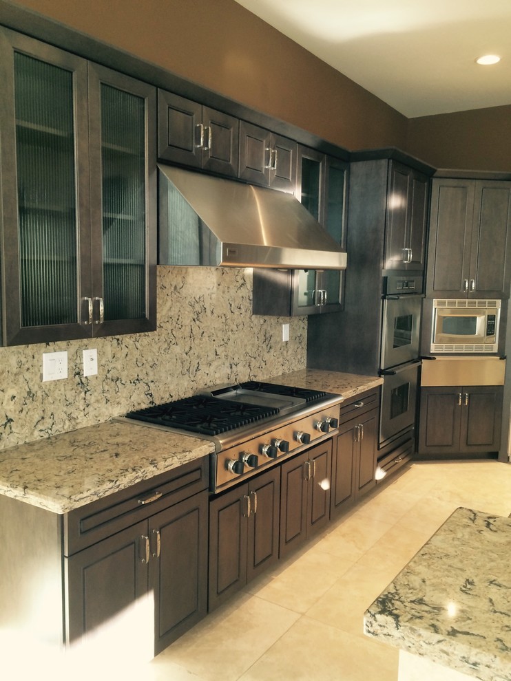 Inspiration for a large transitional l-shaped ceramic tile and beige floor kitchen remodel in Phoenix with a double-bowl sink, granite countertops, multicolored backsplash, stone slab backsplash, stainless steel appliances, raised-panel cabinets, dark wood cabinets and an island