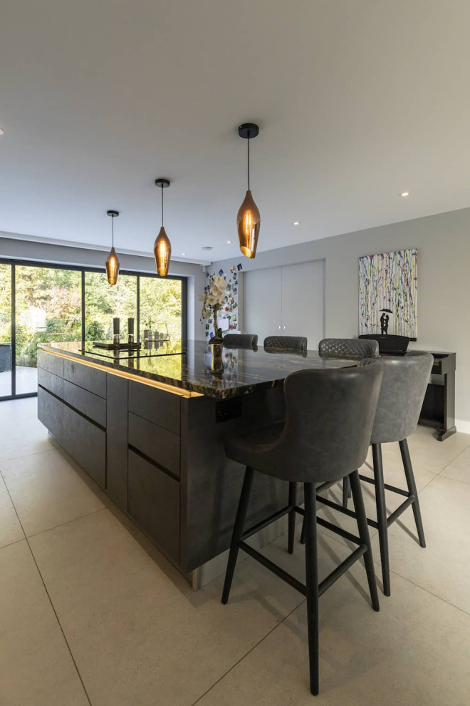 Inspiration for a large modern single-wall open plan kitchen in Hertfordshire with a double-bowl sink, flat-panel cabinets, black cabinets, granite benchtops, metallic splashback, mirror splashback, black appliances, ceramic floors, with island, white floor and black benchtop.