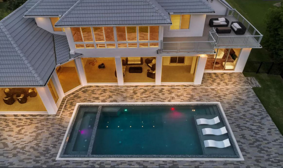 This is an example of a large traditional backyard rectangular pool in Jacksonville with a hot tub and brick pavers.