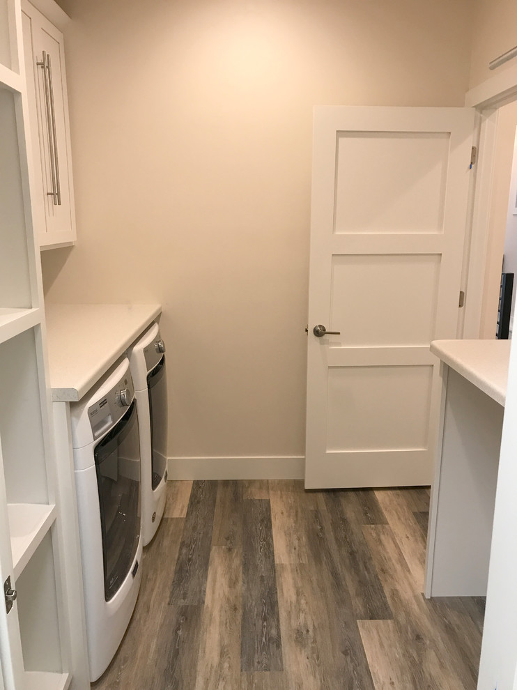 Design ideas for a mid-sized modern single-wall dedicated laundry room in Other with shaker cabinets, white cabinets, laminate benchtops, beige walls, vinyl floors, a side-by-side washer and dryer and multi-coloured floor.