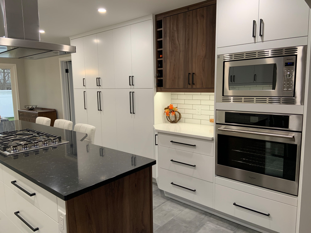 Design ideas for a mid-sized scandinavian galley eat-in kitchen in Edmonton with an undermount sink, flat-panel cabinets, white cabinets, quartz benchtops, white splashback, subway tile splashback, stainless steel appliances, porcelain floors, with island, grey floor and white benchtop.