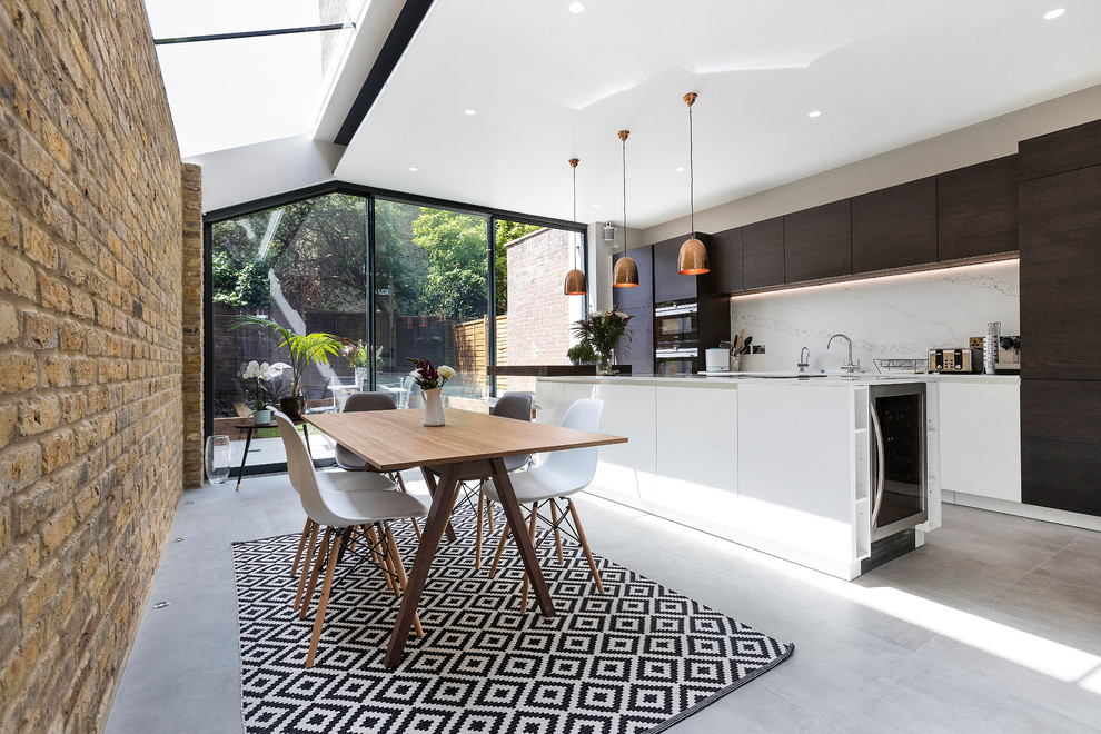 This is an example of a contemporary eat-in kitchen in Other with flat-panel cabinets, marble splashback, with island, white cabinets, white splashback, panelled appliances, grey floor and white benchtop.