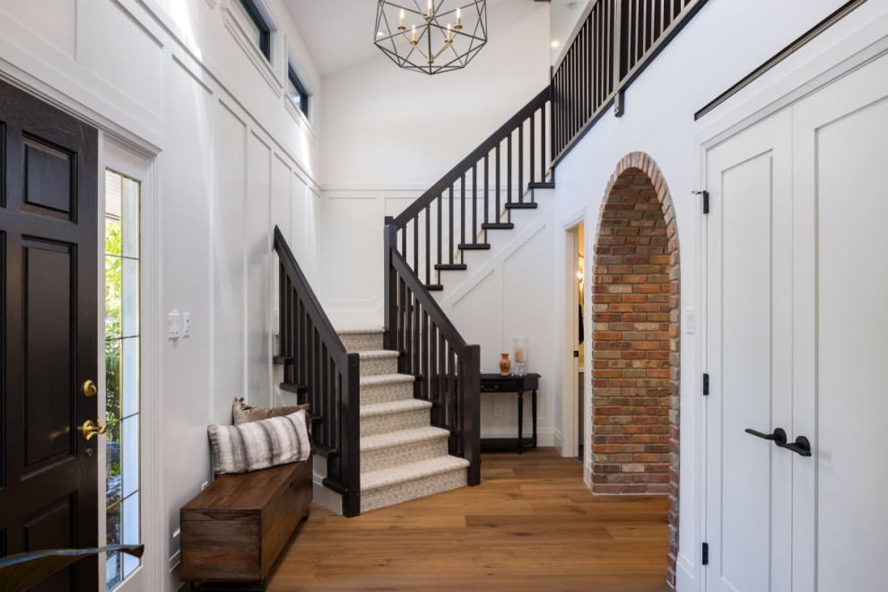 Inspiration for a mid-sized transitional medium tone wood floor, brown floor and wall paneling foyer remodel in Vancouver with white walls and a black front door