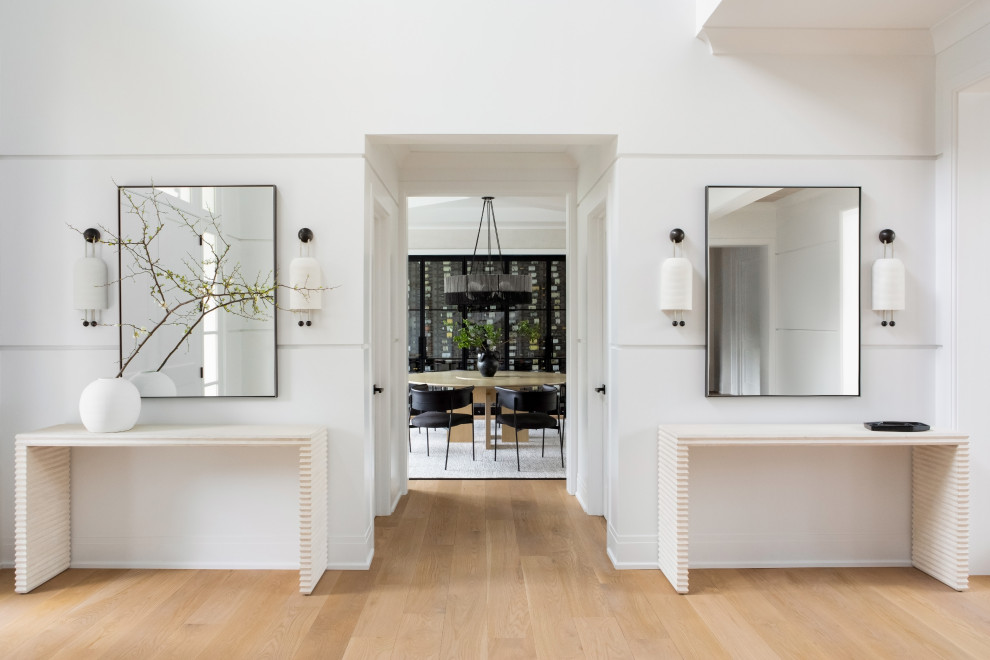 This is an example of a large transitional front door in New York with white walls, light hardwood floors, a double front door, a white front door, brown floor, vaulted and wood walls.