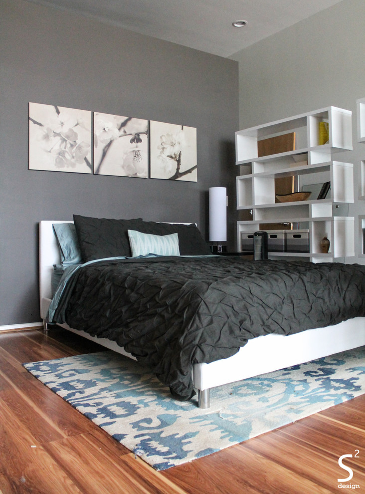 This is an example of an industrial loft-style bedroom in Houston with grey walls and medium hardwood floors.