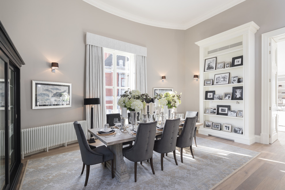 This is an example of a mid-sized transitional separate dining room in London with grey walls and light hardwood floors.