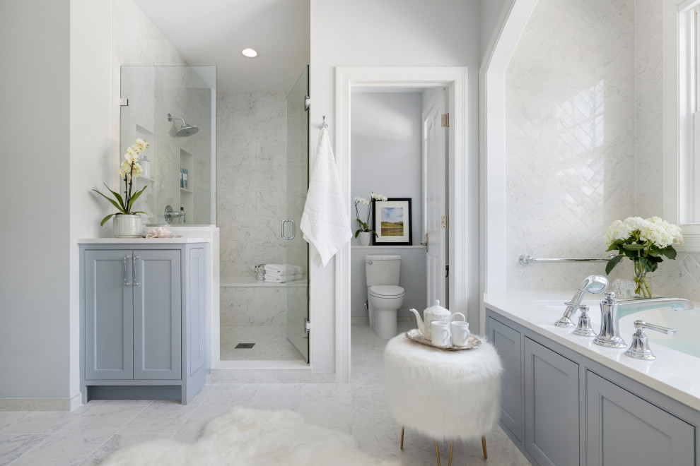 Idée de décoration pour une douche en alcôve principale avec un placard avec porte à panneau encastré, des portes de placard bleues, une baignoire encastrée, WC séparés, un carrelage blanc, du carrelage en marbre, un mur gris, un sol en marbre, un lavabo encastré, un plan de toilette en quartz modifié, un sol blanc, une cabine de douche à porte battante, un plan de toilette blanc, meuble double vasque, meuble-lavabo encastré et des toilettes cachées.