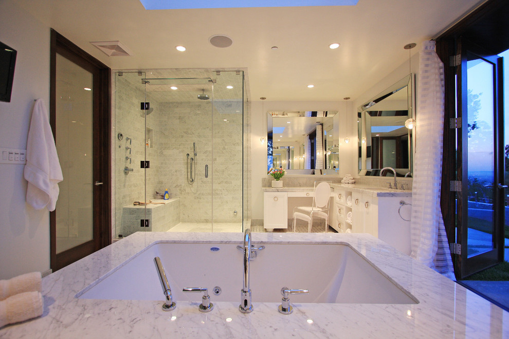 This is an example of a contemporary bathroom in Los Angeles with flat-panel cabinets, white cabinets, a drop-in tub, an alcove shower and white tile.