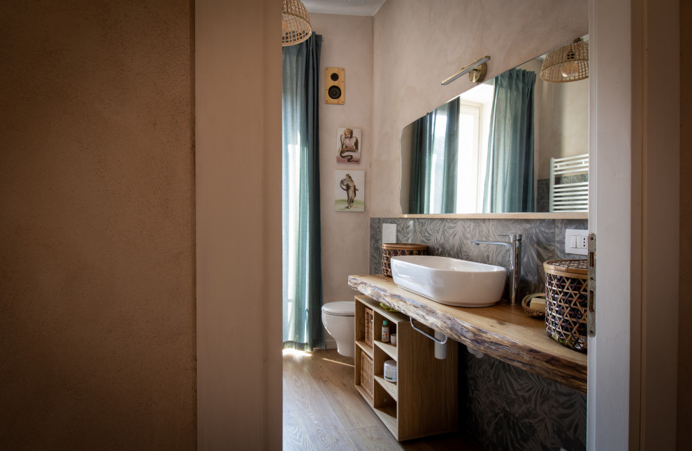 Exempel på ett mycket stort eklektiskt badrum, med öppna hyllor, skåp i mörkt trä, ett platsbyggt badkar, en vägghängd toalettstol, grön kakel, porslinskakel, rosa väggar, laminatgolv, ett fristående handfat, träbänkskiva och beiget golv