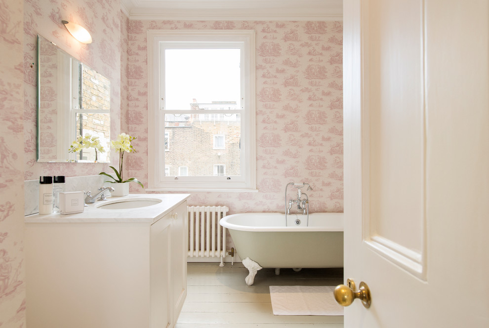 Design ideas for a traditional bathroom in London with shaker cabinets, white cabinets, a claw-foot tub, pink tile, pink walls, light hardwood floors, an undermount sink and white floor.
