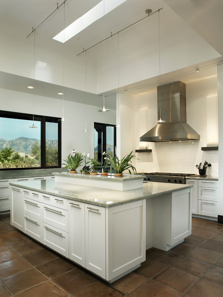 This is an example of a large contemporary kitchen in Phoenix with shaker cabinets, white cabinets, white splashback, ceramic splashback, stainless steel appliances, terra-cotta floors, with island and brown floor.