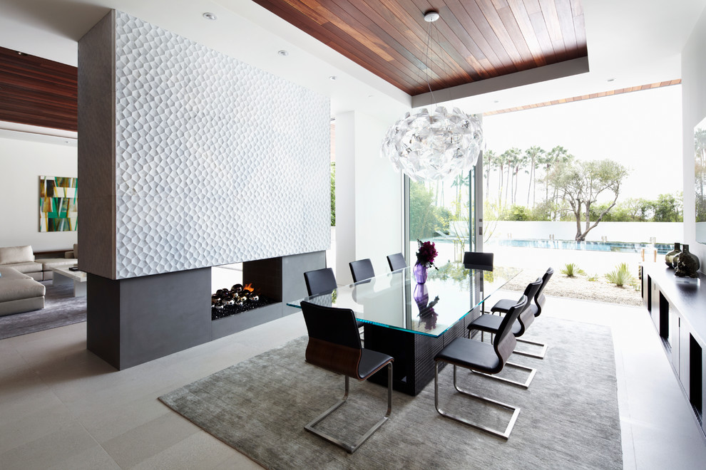 Large contemporary separate dining room in Los Angeles with white walls, a two-sided fireplace, a concrete fireplace surround and ceramic floors.