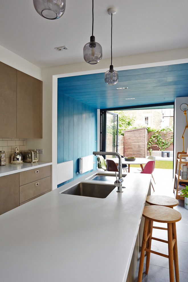 This is an example of a contemporary kitchen in London with flat-panel cabinets and with island.