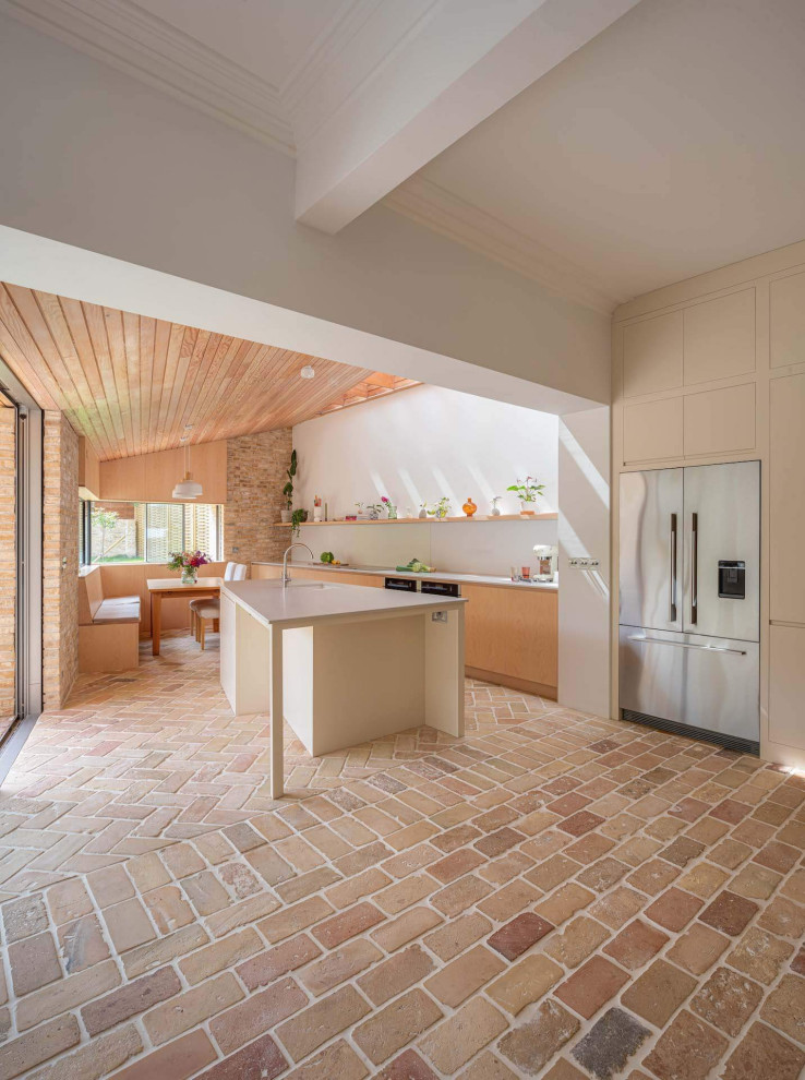 Exemple d'une grande cuisine ouverte linéaire scandinave en bois clair avec un placard à porte plane, un plan de travail en surface solide, un sol en brique, îlot et un plan de travail gris.