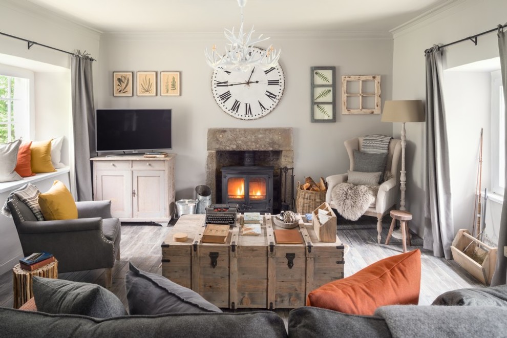 Small country enclosed living room in Glasgow with white walls, a freestanding tv, grey floor, a wood stove and a metal fireplace surround.