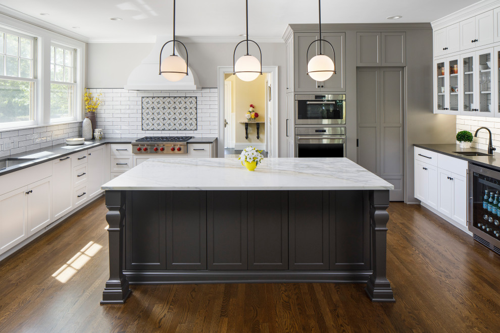 This is an example of a classic u-shaped kitchen pantry in Minneapolis with recessed-panel cabinets, grey cabinets, engineered stone countertops, white splashback, ceramic splashback, stainless steel appliances, dark hardwood flooring, an island and grey worktops.