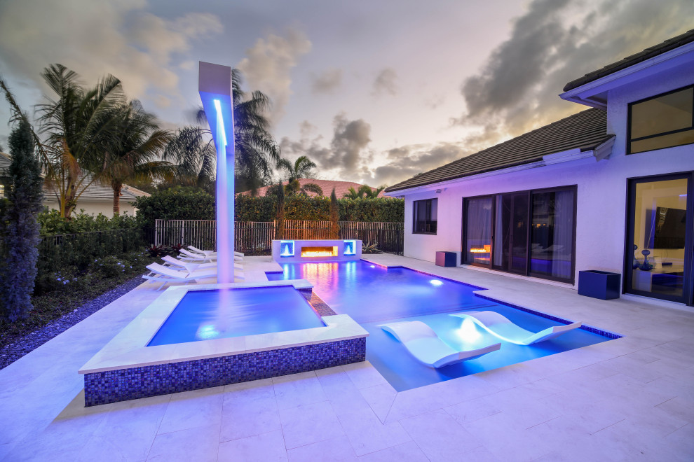Esempio di una grande piscina monocorsia minimalista personalizzata dietro casa con una vasca idromassaggio e pavimentazioni in pietra naturale