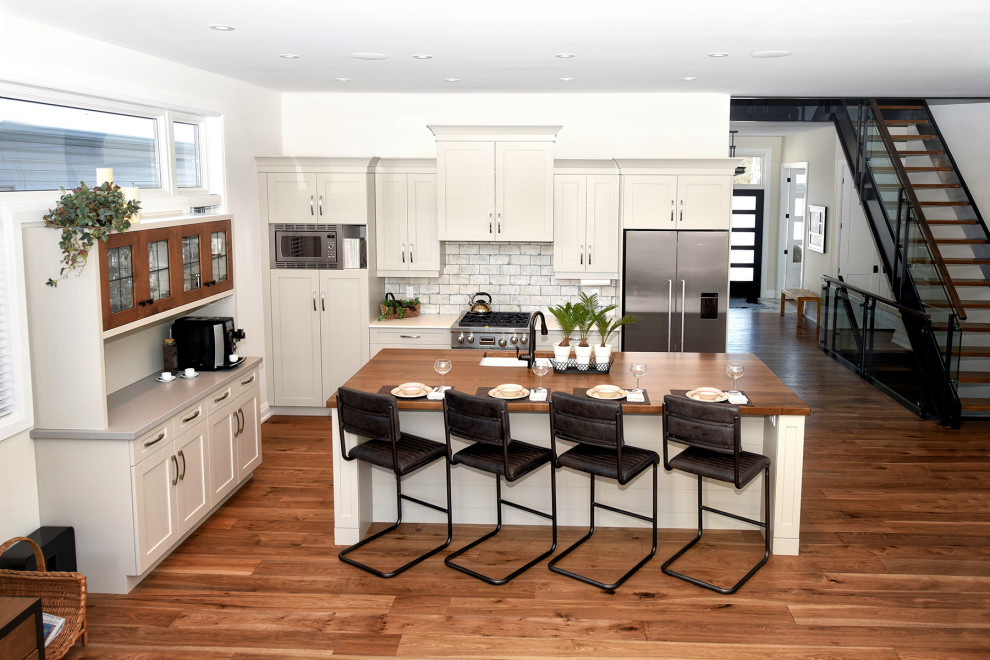 Mid-sized arts and crafts medium tone wood floor kitchen photo with a double-bowl sink, recessed-panel cabinets, gray cabinets, solid surface countertops, multicolored backsplash, porcelain backsplash, stainless steel appliances, an island and white countertops