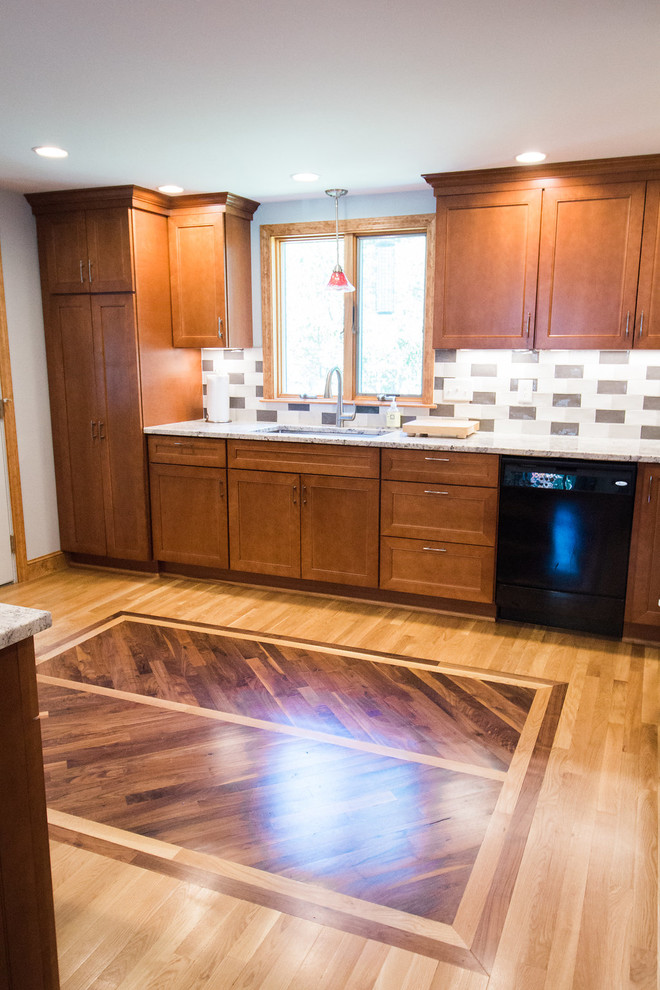 Example of a mid-sized transitional u-shaped medium tone wood floor eat-in kitchen design in Boston with an undermount sink, recessed-panel cabinets, medium tone wood cabinets, granite countertops, multicolored backsplash, subway tile backsplash, black appliances and a peninsula