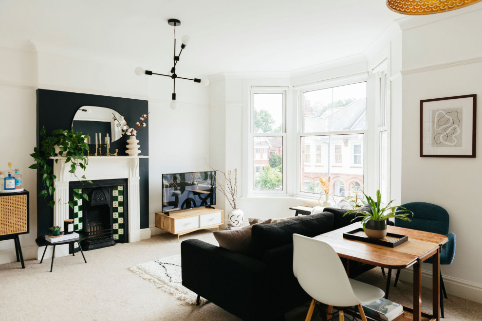 This is an example of a large traditional formal open plan living room in London with white walls, carpet, a standard fireplace, a tiled fireplace surround, a corner tv, beige floors and a chimney breast.