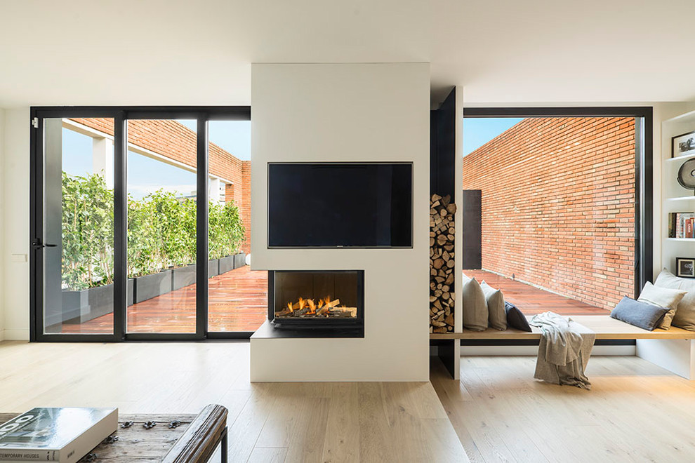 Large contemporary open concept family room in Barcelona with white walls, medium hardwood floors, a corner fireplace, a concrete fireplace surround and a wall-mounted tv.