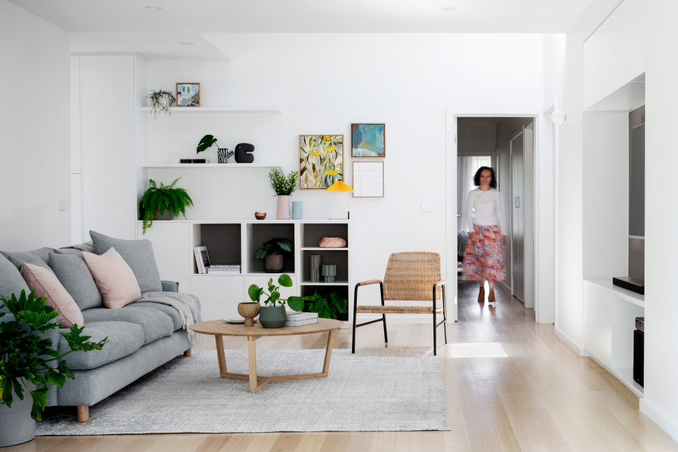 Abgetrenntes Modernes Wohnzimmer ohne Kamin mit weißer Wandfarbe, hellem Holzboden und Multimediawand in Melbourne