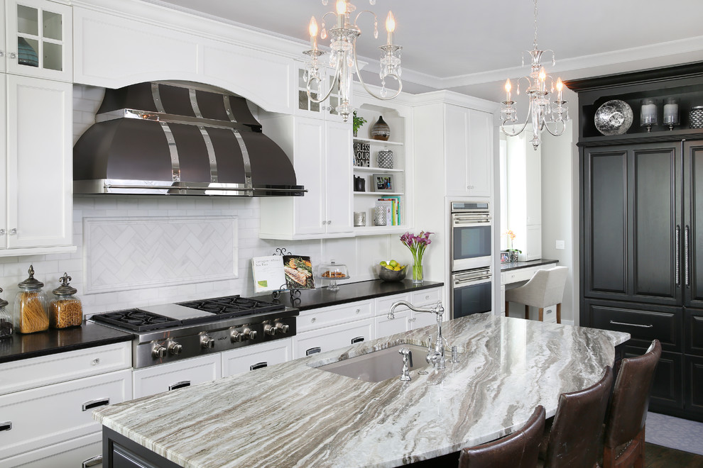 Photo of a large traditional u-shaped eat-in kitchen in Chicago with an undermount sink, white cabinets, quartz benchtops, white splashback, subway tile splashback, stainless steel appliances, dark hardwood floors, with island and recessed-panel cabinets.