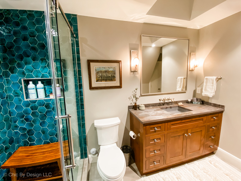 Example of a mountain style blue tile and terra-cotta tile ceramic tile and gray floor sliding shower door design with shaker cabinets, brown cabinets, a two-piece toilet, gray walls, an undermount sink, quartz countertops and gray countertops