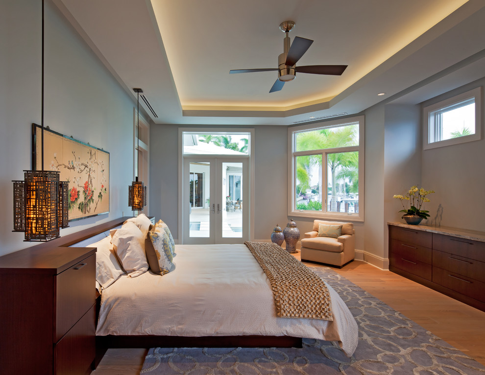 This is an example of a large contemporary master bedroom in Miami with blue walls and light hardwood floors.