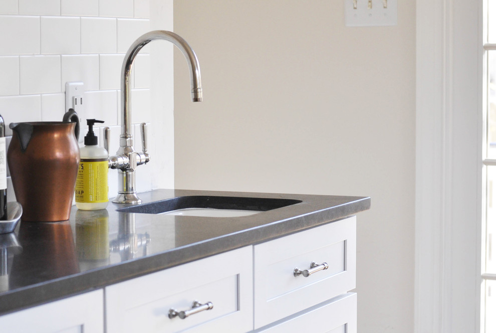 Home design - mid-sized transitional l-shaped medium tone wood floor home design idea in Richmond with a farmhouse sink, shaker cabinets, white cabinets, granite countertops, white backsplash, subway tile backsplash and stainless steel appliances